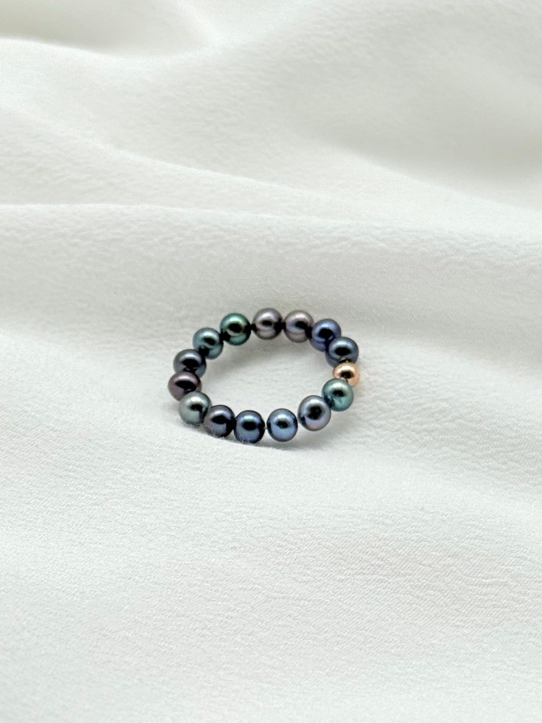 Mina Peacock Ring aus dunklen Peacock-Perlen stilvoll auf Seidenstoff präsentiert – minimalistischer Perlenschmuck von Simply O Jewelry.