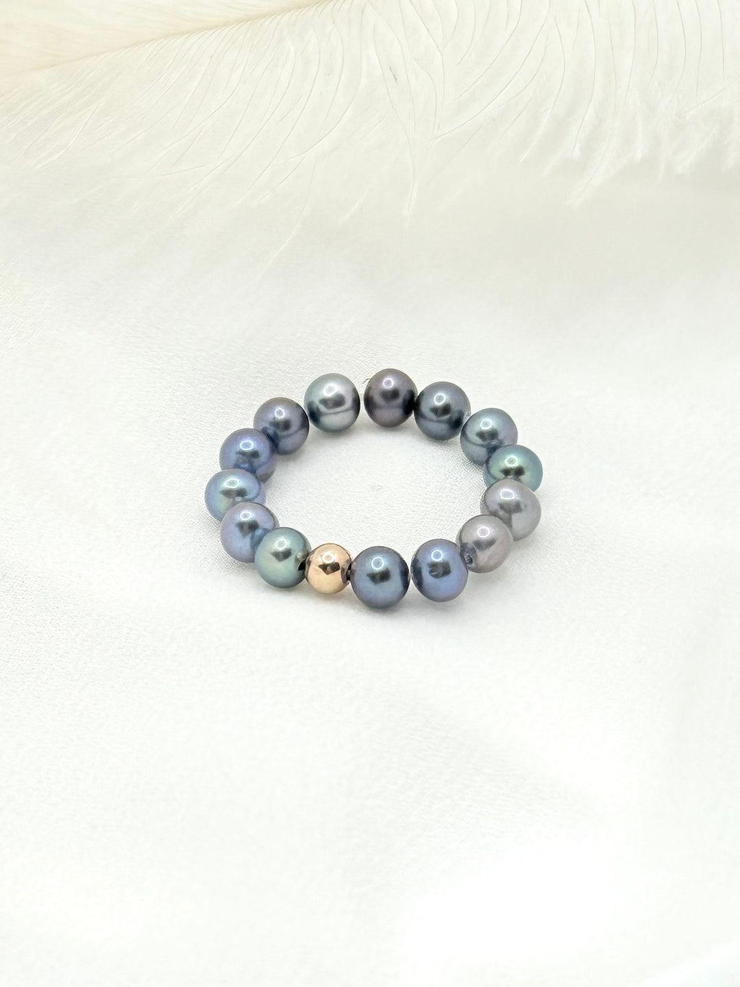 Mina Peacock Ring aus schimmernden Peacock-Süßwasserperlen auf hellem Stoff arrangiert – eleganter handgefertigter Ring.