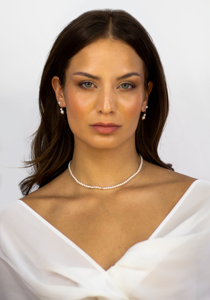 Model trägt Dorée Perlenkette mit weißem Kleid – runde Süßwasserperlen mit Goldakzent - SimplyO